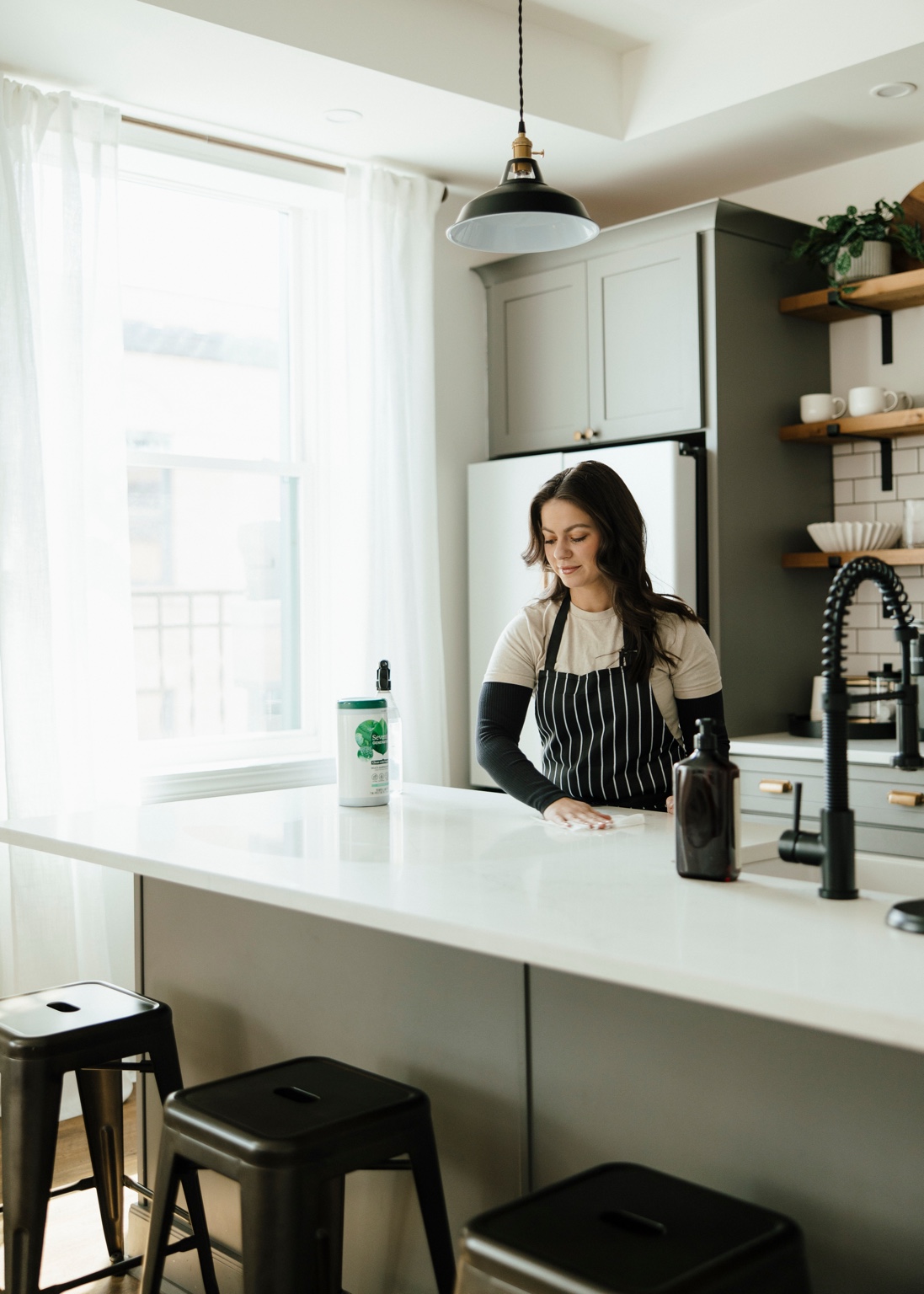 The owner of EVE Home Services cleaning a bright kitchen.