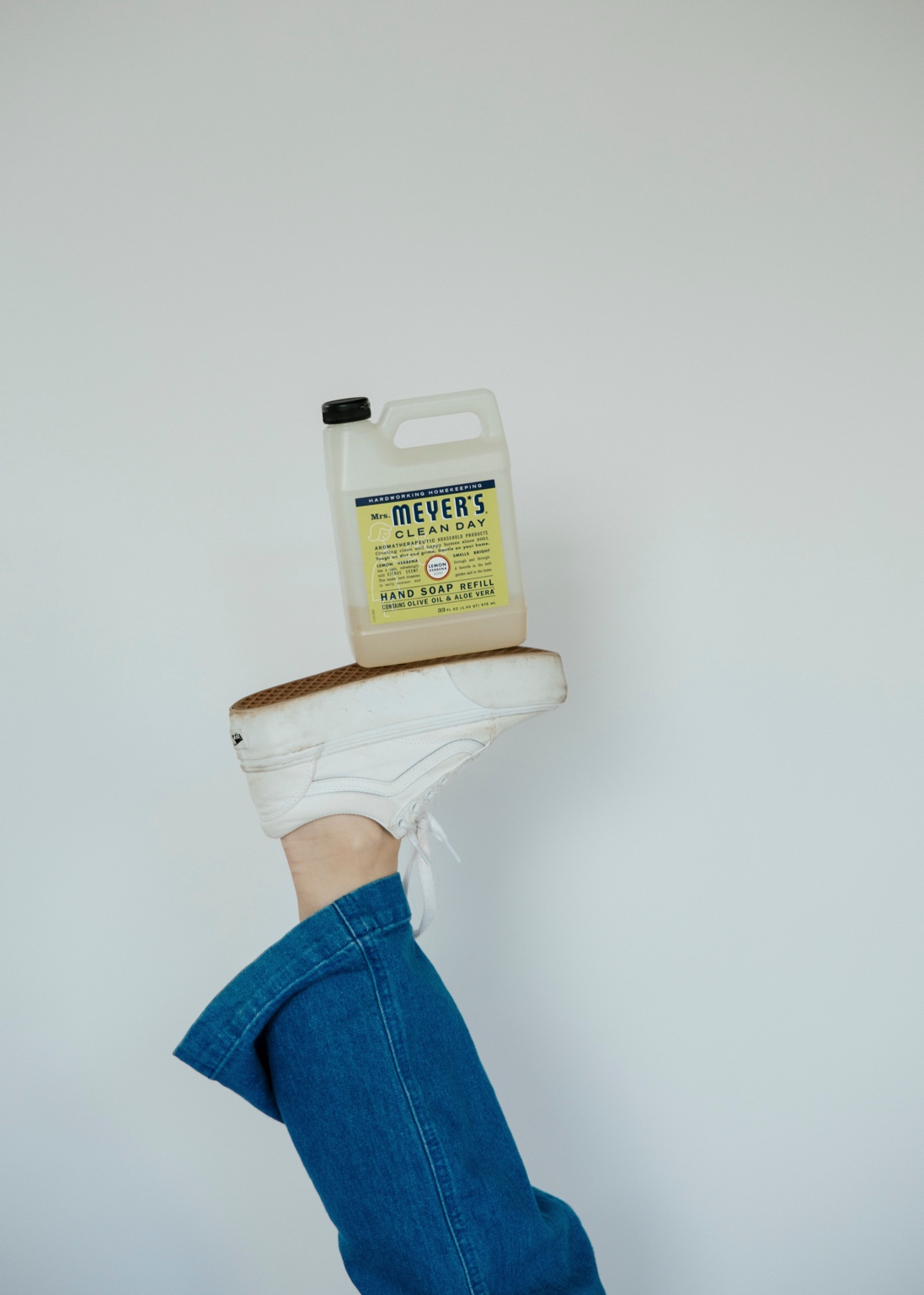 A hand soap refill bottle balanced on a sneaker in a playful brand photo.