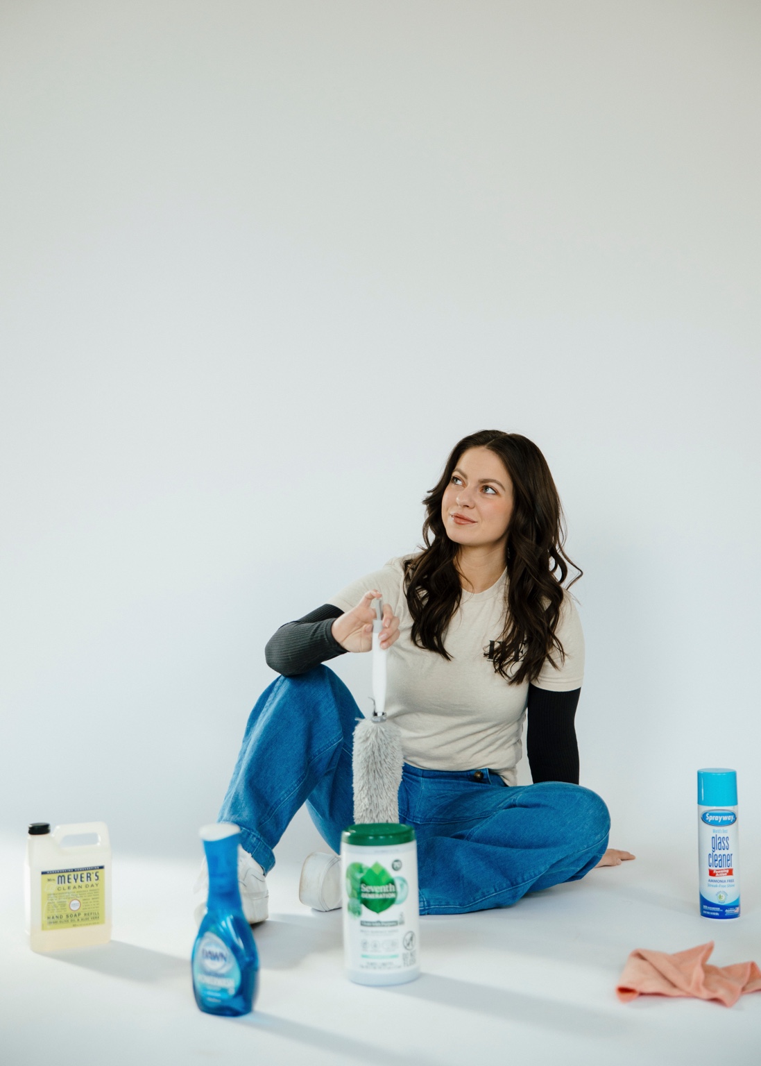 The owner of EVE Home Services sitting in a studio with cleaning products nearby.